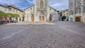 Un edificio histórico con una entrada central en arco, fachada de piedra y un patio empedrado.