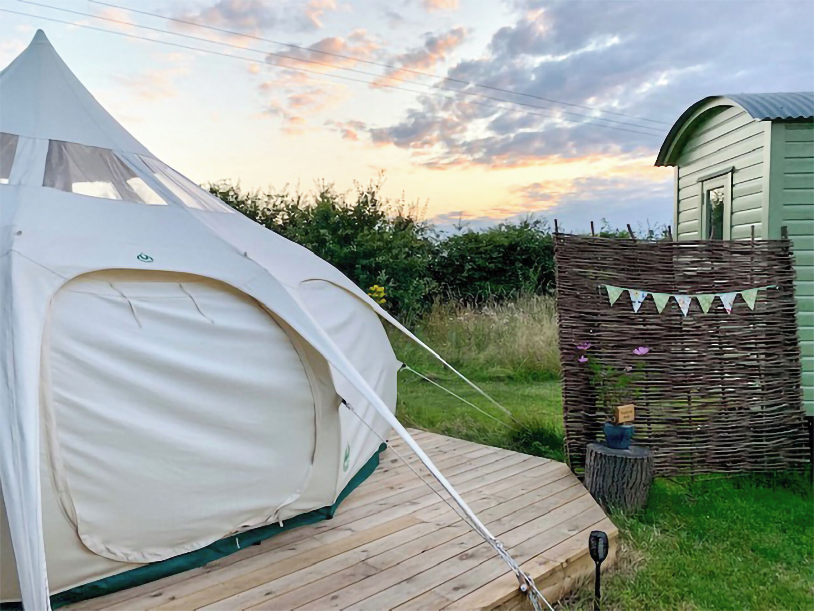 A tent on a wooden deck, a small shed, and a decorative fence with bunting.