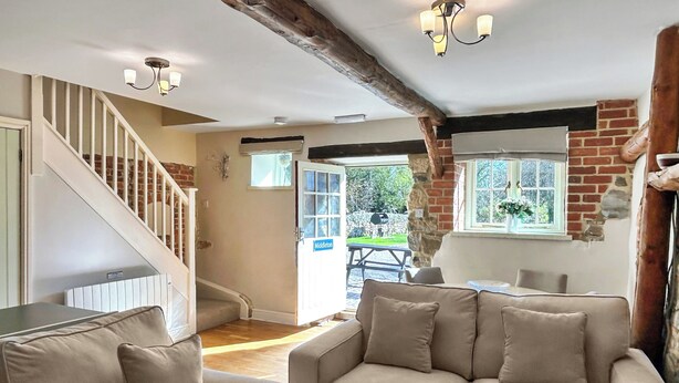 A living room with a sofa set, a staircase, and a view of the outside. - 2 bedroom accommodation in Carsington, near Ashbourne (Carsington, near Ashbourne)