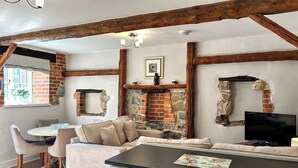 A cozy room with exposed wooden beams, a brick wall, a sofa, a dining table, and a television. - 2 bedroom accommodation in Carsington, near Ashbourne (Carsington, near Ashbourne)
