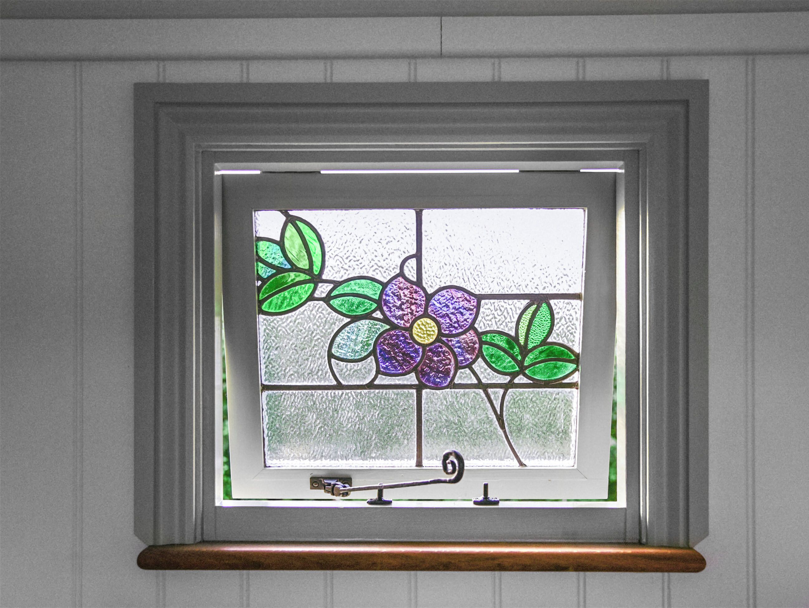 A window with a stained glass design featuring purple and green leaves.