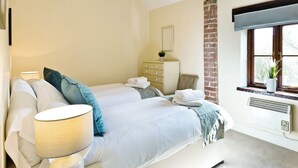 Una camera da letto con un letto, una cassettiera, una sedia, una finestra vista e un termosifone.