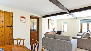 A room with a wooden dining table, two sofas, a television, and a fireplace. - Spacious stone barn close to Matlock and Carsington Water. (Carsington, near Ashbourne)