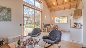A spacious living area with a wooden ceiling, large windows, and a dining area. - Le Chalet Morets - Avec vue sur la montagne (Saint-Gervais-les-Bains)
