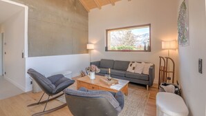 A living room with a sofa, a rocking chair, a coffee table, and a window with a view. - Le Chalet Morets - Avec vue sur la montagne (Saint-Gervais-les-Bains)