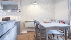 Ett modernt kök med matplats, en inbyggd ugn, en kaffemaskin och en vit taklampa.