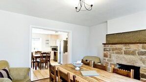 A dining area with a wooden table, chairs, a laptop, and a stone fireplace.