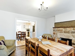 A dining area with a wooden table, chairs, a laptop, and a stone fireplace.