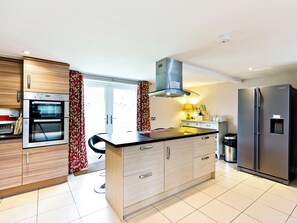 Een moderne keuken met inbouwapparatuur, een centraal kookeiland en uitzicht op het exterieur.