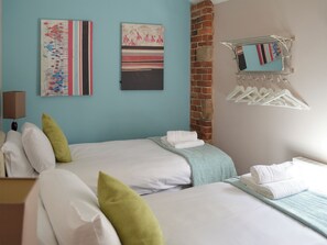 A hotel room with two beds, a brick wall, a wall-mounted towel rack, and abstract art on the wall. - 4 bedroom accommodation in Carsington, near Ashbourne (Carsington, near Ashbourne)