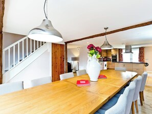 A dining area with a wooden table, chairs, a white vase with flowers, and pendant lighting. - 4 bedroom accommodation in Carsington, near Ashbourne (Carsington, near Ashbourne)