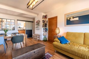 Ein Wohnzimmer mit einer Couch, einem Esstisch und einer Küche im Hintergrund.