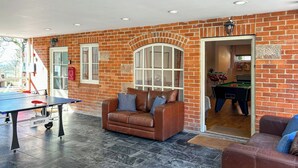 A room with a billiards table, a leather sofa, a brick wall, and a window. - 3 bedroom accommodation in Carsington, near Ashbourne (Carsington, near Ashbourne)