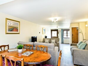 Ein Wohnzimmer mit Esstisch, Sofas und Fernseher.