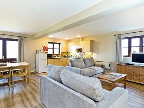 Ein gemütlicher Wohnbereich mit Küchenzeile, einer Couch, einem Esstisch und einem Fernseher.