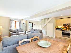 A living room with a sofa set, a dining table with a plate, a staircase, and a kitchen area. - 2 bedroom accommodation in Carsington, near Ashbourne (Carsington, near Ashbourne)