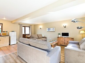 A living room with a sofa, TV, and a small table with a plant. - 2 bedroom accommodation in Carsington, near Ashbourne (Carsington, near Ashbourne)