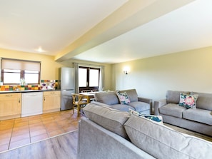 A compact living space with a kitchenette, sofa, dining table, and a window.