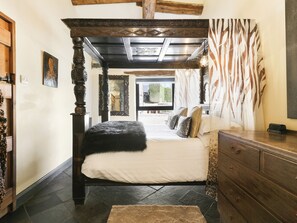 Une chambre à coucher avec un lit à baldaquin, une commode en bois et un rideau à motifs zébrés.