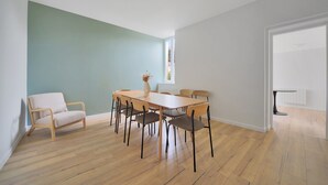 Ein Essbereich mit Holztisch und Stühlen, einer hellblauen Wand und Blick durch eine offene Tür.
