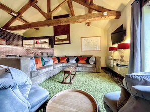 A living room with a sectional sofa, a wooden coffee table, and a TV.