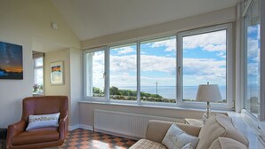 A room with a large window, a sofa, a chair, and a radiator.