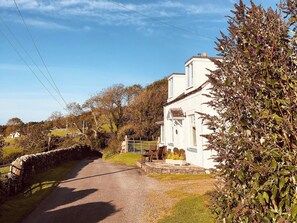 A white house with a stone wall and a gravel path leading to it. - 2 bedroom accommodation in Near Gatehouse of Fleet (Near Gatehouse of Fleet)
