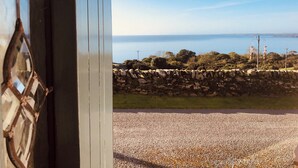 A stone wall, a clear sky, and a view of the sea.