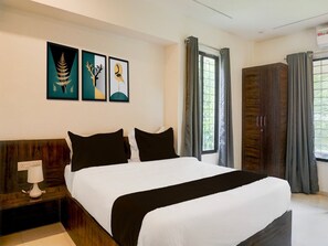 A bedroom with a bed, nightstand, and artwork on the wall. - Hotel O Laxman Nagar Baner (Pune)