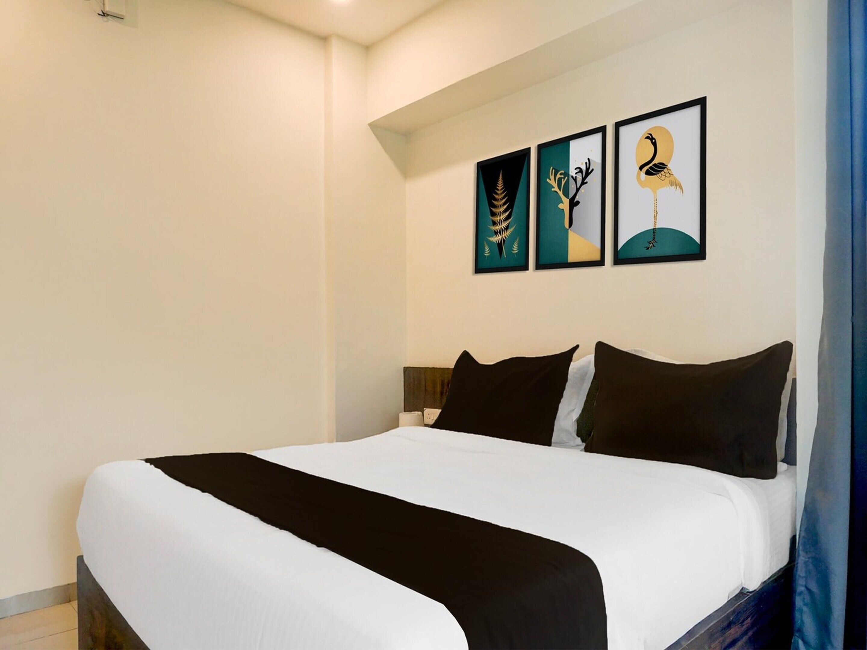 Een hotelkamer met een groot bed, een hoofdbord en drie ingelijste kunstwerken aan de muur.