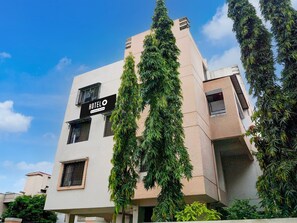 A modern hotel building with a sign reading 'HOTEL' and a company name. - Hotel O Laxman Nagar Baner (Pune)