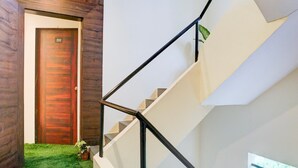 A modern staircase with a wooden door labeled '202' and a small potted plant on the landing. - Hotel O Laxman Nagar Baner (Pune)