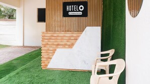 A hotel reception area with a wooden wall, a marble counter, and a sign indicating it is company-serviced. - Hotel O Laxman Nagar Baner (Pune)