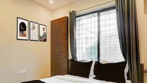 A bedroom with a bed, a wardrobe, and a window with curtains. - Hotel O Laxman Nagar Baner (Pune)