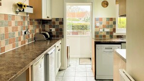 Een keuken met een betegelde spatwand, een vaatwasser en een klok aan de muur.