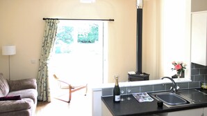 Una cocina compacta con un lavamanos integrado, un refrigerador pequeño y una ventana con cortinas.