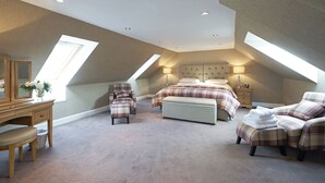 Una camera da letto con soffitto spiovente, lucernari, un letto, una sedia, una scrivania e un comò.