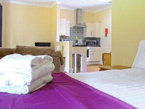 Ein Hotelzimmer mit einem Bett, einer kleinen Küchenzeile, einem Fernseher und einem Sofa.