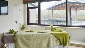 Een kamer met een bed, een raam, een radiator en een kleine plant.