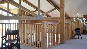 Ein Zimmer mit Holzbalkendecke, einem schwarzen Stuhl und einem Blumentopf.