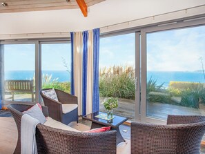 A room with wicker furniture, a glass table, and a view of the sea. - Shark Fin completely has the wow factor. (Sennen)