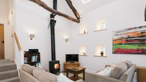 Un soggiorno accogliente con camino, posti a sedere confortevoli, una televisione e un quadro appeso al muro.