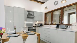Una cucina moderna con mobili bianchi, un tavolo da pranzo in legno e una finestra con vista.