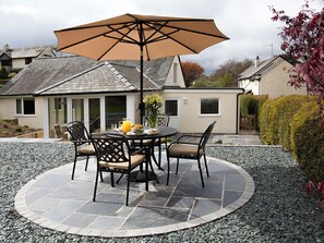 An outdoor patio with a round table, chairs, and a large umbrella.