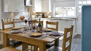 A modern kitchen with white cabinets, a dining table set for six, and a blue refrigerator. - 3 bedroom accommodation in Ambleside (Ambleside)