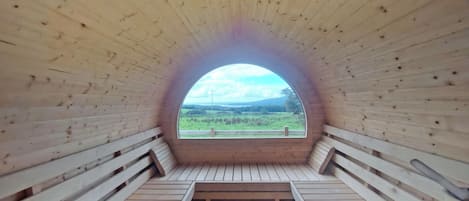 Een ronde houten constructie met uitzicht op een groen landschap door een groot raam.