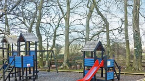 A playground with wooden play structures, including slides and climbing areas, surrounded by trees. - 2 bedroom accommodation in Carsington, near Ashbourne (Carsington, near Ashbourne)