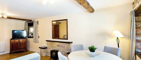 A living room with a fireplace, a television, and a round dining table with chairs.
