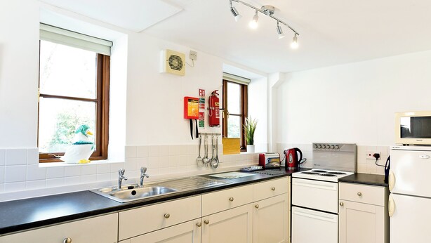 A kitchen with white cabinets, a stove, a microwave, and a sink. - 2 bedroom accommodation in Carsington, near Ashbourne (Carsington, near Ashbourne)