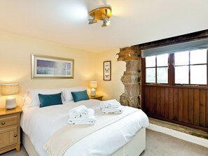 A bedroom with a bed, two bedside tables, a lamp, a framed picture, and a window with a view.